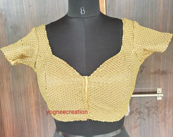 May include: Gold-colored, short-sleeved blouse with a square neckline and a subtle, textured pattern. The blouse is displayed on a black mannequin, showcasing its design and fit. The text "yogheecreation" is visible on the bottom of the blouse.