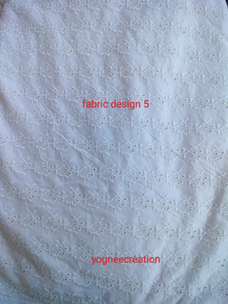 Puede incluir: Tela blanca con un patr&oacute;n floral bordado. La tela tiene una apariencia delicada y texturizada. Las palabras "fabric design 5" y "yogneecre&aacute;tion" est&aacute;n impresas en la tela.