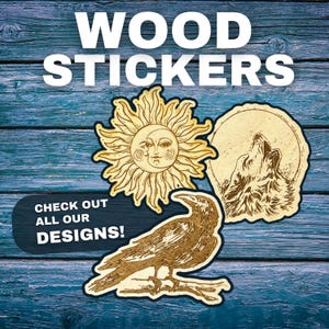 Pode incluir: Três adesivos de madeira em um fundo de madeira azul. Os adesivos apresentam um sol com um rosto, um lobo uivando para a lua e um corvo. O texto "WOOD STICKERS" está no topo da imagem e o texto "CHECK OUT ALL OUR DESIGNS!" está na parte inferior.