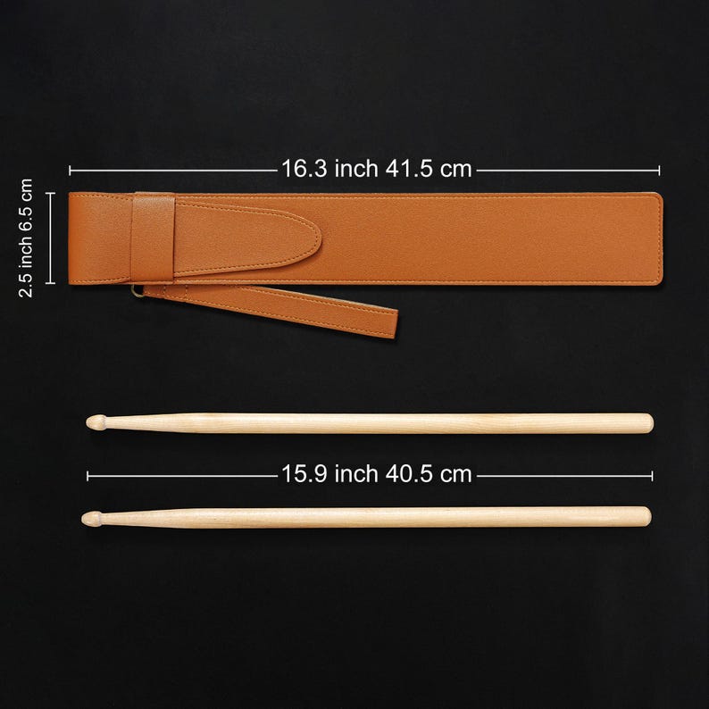 May include: A brown leather drumstick case, 16.3 inches (41.5 cm) long, with a flap closure and a carrying strap. Two wooden drumsticks, each 15.9 inches (40.5 cm) long, are positioned below the case against a black background.