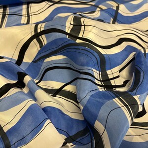 Pode incluir: Tecido listrado azul e branco com linhas abstratas pretas. O tecido é transparente e tem uma textura sedosa.