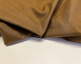 May include: A close-up of a brown linen fabric with a subtle texture. The fabric is folded and draped, showcasing its soft and natural appearance.