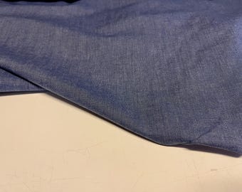 May include: A close-up of a piece of blue denim fabric. The fabric has a soft, textured surface.