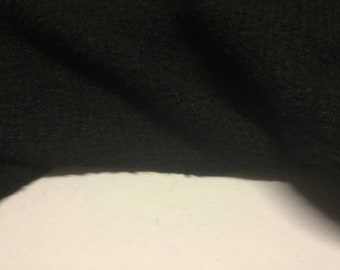 Puede incluir: Primer plano de una tela negra con una textura suave y peluda. La tela está doblada y drapeada, mostrando su textura y caída.