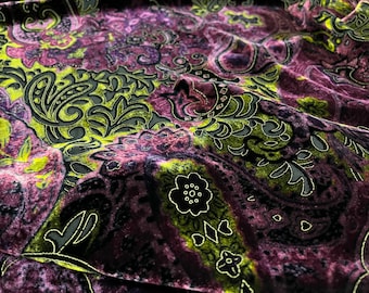 May include: Close-up of a purple velvet fabric with a black and green paisley pattern.