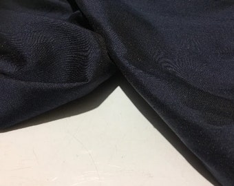May include: A close-up of a dark blue fabric with a smooth, silky texture. The fabric is folded and draped, showcasing its luxurious feel.