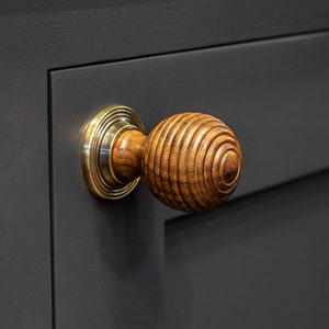 May include: A wooden door knob with a brass base. The knob has a ribbed design and is a dark brown colour.