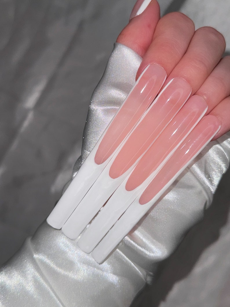May include: Long, white, and pink acrylic nails with a white tip design.