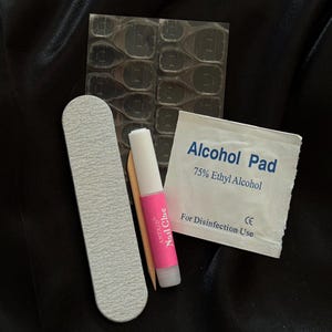 May include: A set of nail art supplies including a nail file, a small bottle of nail glue, a pack of adhesive tabs, and an alcohol pad labeled "Alcohol Pad 75% Ethyl Alcohol For Disinfection Use CE"
