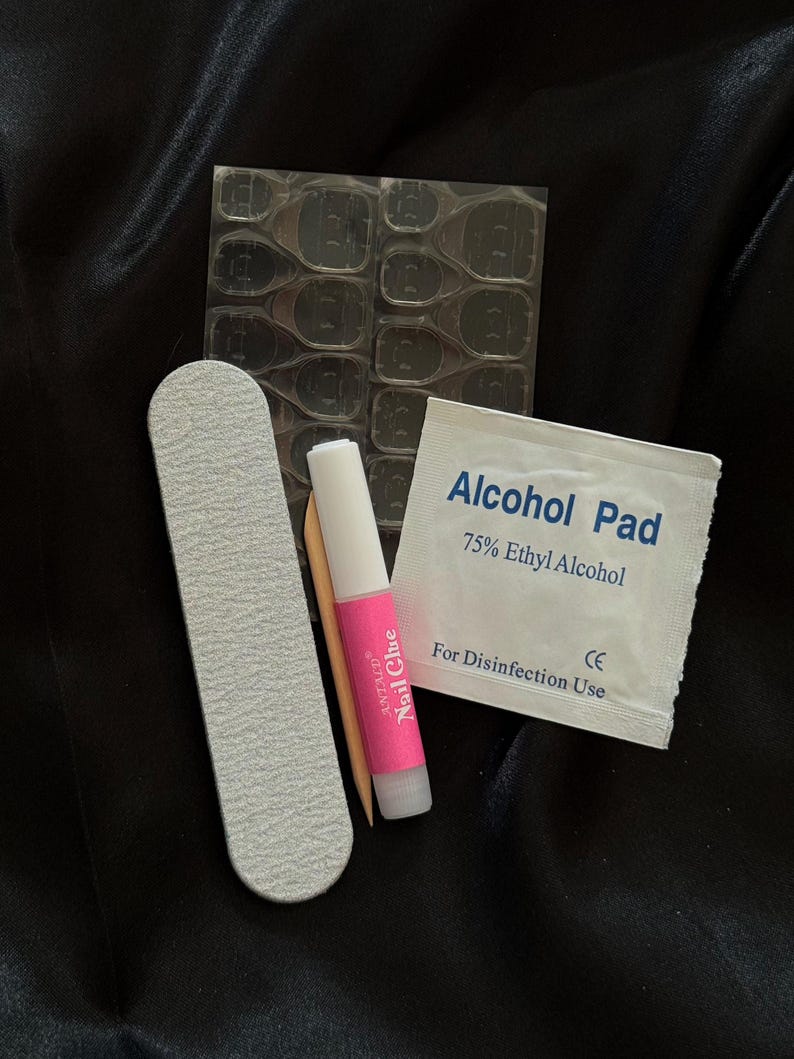 May include: A set of nail art supplies including a nail file, a small bottle of nail glue, a pack of adhesive tabs, and an alcohol pad labeled "Alcohol Pad 75% Ethyl Alcohol For Disinfection Use CE"