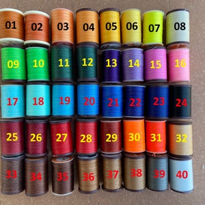 May include: Forty spools of thread in various colors, numbered 01 to 40. The spools are arranged in four rows of ten spools each.