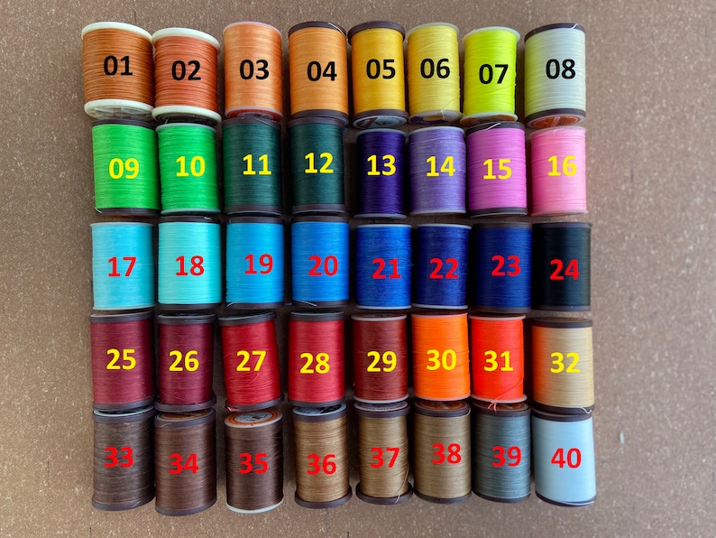 May include: Forty spools of thread in various colors, numbered 01 to 40. The spools are arranged in four rows of ten spools each.
