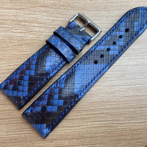 Könnte beinhalten: Ein blaues und schwarzes Schlangenleder-Armband mit blauen Nähten. Das Armband ist aus echtem Leder und hat eine silberne Schnalle.