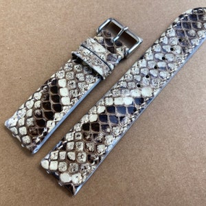 May include: A brown and white snakeskin watch strap with a silver buckle.