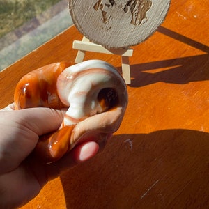 May include: A hand holds a brown and white slime with swirls. A wooden sign with the text "Dunn with love slimes" is in the background.