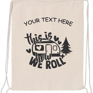 May include: A white canvas drawstring bag with black text that reads "This is how we roll" and a black silhouette of a camper with a heart inside. The text "YOUR TEXT HERE" is at the top of the bag.