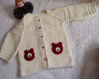 Cárdigan de lana tejido a mano para bebé, con aplique de oso color crema.