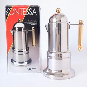 May include: A stainless steel espresso maker with a gold-colored handle and accents. The product is displayed next to its original box, which features the brand name "KONTESSA" in bold letters.