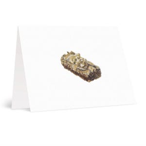 May include: A blank greeting card featuring a watercolour painting of a log-shaped pastry. The pastry is brown with beige and tan details, set against a white background. The card is folded and standing upright.