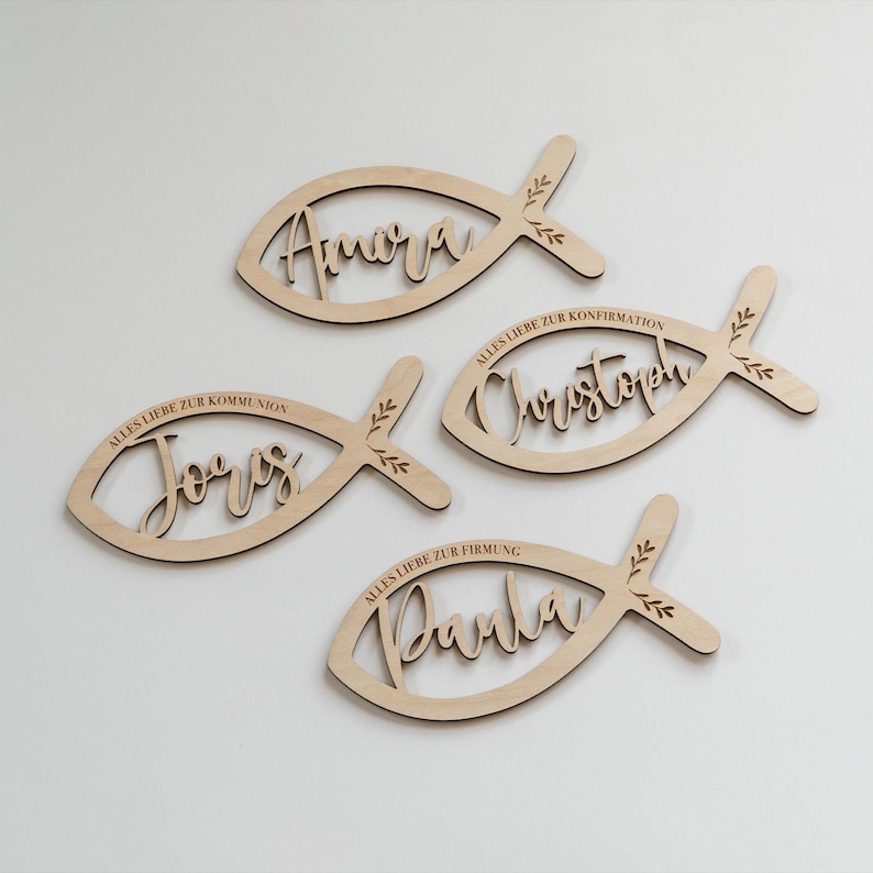 K&ouml;nnte beinhalten: Vier Holzdekorationen in Fischform mit Namen und S&auml;tzen auf Deutsch. Jeder Fisch hat einen Namen in Schreibschrift: Amora, J&ouml;rg, Christoph und Darla. Die S&auml;tze beinhalten "Alles Liebe zur Konfirmation" und "Alles Liebe zur Kommunion".