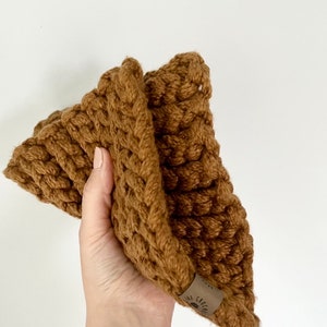 May include: A brown crocheted hat with a small brown label that says "The Cozy Co."
