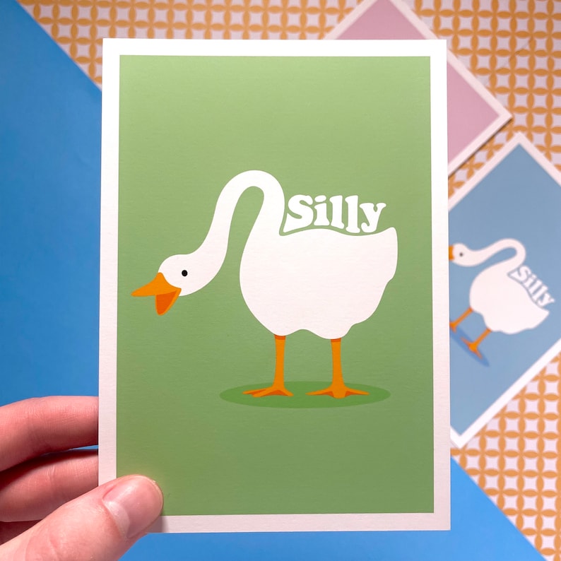 K&ouml;nnte beinhalten: Eine gr&uuml;ne Karte mit einer wei&szlig;en G&auml;nse-Illustration und dem Wort "Silly" in orangefarbenen Buchstaben. Die Gans schaut nach links und hat den Kopf geneigt.
