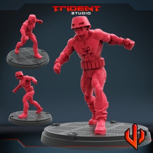 May include: A red plastic miniature figure of a superhero wearing a helmet and a red and white costume. The figure is standing on a round base with a textured surface. The figure is posed in a dynamic action pose with one arm raised and the other arm bent at the elbow. The figure is painted in a bright red color with white accents. The figure is a 3D printed model.