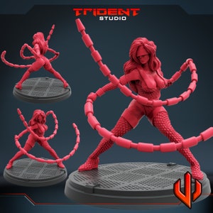 May include: A red figurine of a female character in a dynamic pose, wearing a blindfold and a textured bodysuit. The figure is holding segmented, chain-like appendages. The base is a dark gray platform. The Trident Studio logo is visible.