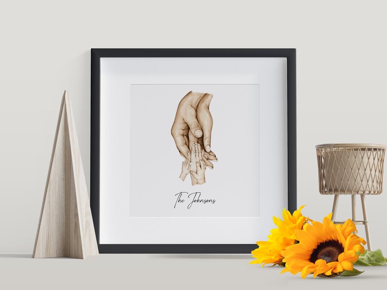 Op de afbeelding: Een aquarel-illustratie van een grote hand die de handen van twee kleinere handen vasthoudt. De afbeelding is ingelijst in zwart en wit en heeft de tekst "The Johnsons" onderaan.