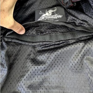 May include: Black mesh fabric with a Speed and Strength logo patch. The patch features a bull graphic and the text "Speed and Strength". The interior of the garment is visible, showing a pocket.