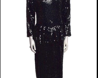 May include: A black sequin dress with long sleeves and a knee-length skirt. The dress is covered in small, reflective sequins, creating a shimmering effect. The dress has a round neckline and a fitted silhouette, suitable for formal occasions.