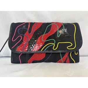 Puede incluir: Bolso de mano negro con cierre de solapa. La parte delantera presenta un diseño de material similar a piel de serpiente roja y negra, con costuras coloridas en rosa, amarillo, verde y azul. El bolso tiene una correa negra.