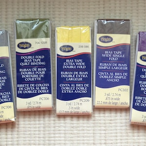 May include: Five packages of Wrights bias tape in various colors, including gray, olive green, yellow, brown, and purple. Each package is labeled with the product name, measurements of 3 yards (2.74 m) and .875 inches wide, and the text "Double Fold Bias Tape Quilt Binding".