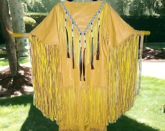 May include: A yellow leather dress with fringe and beadwork. The dress has a V-neckline and is decorated with blue and white beads. The fringe is long and flowing, and the dress is made of soft, supple leather.