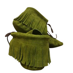 May include: Olive green suede moccasin boots with fringe detailing. The boots have a rounded toe and brown leather laces. The fringe is around the top of the boot.