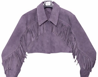 May include: A cropped, lilac suede jacket with long sleeves and a collar. The jacket features fringe detailing across the chest and along the sleeves. The jacket is hanging on a hanger against a white background.