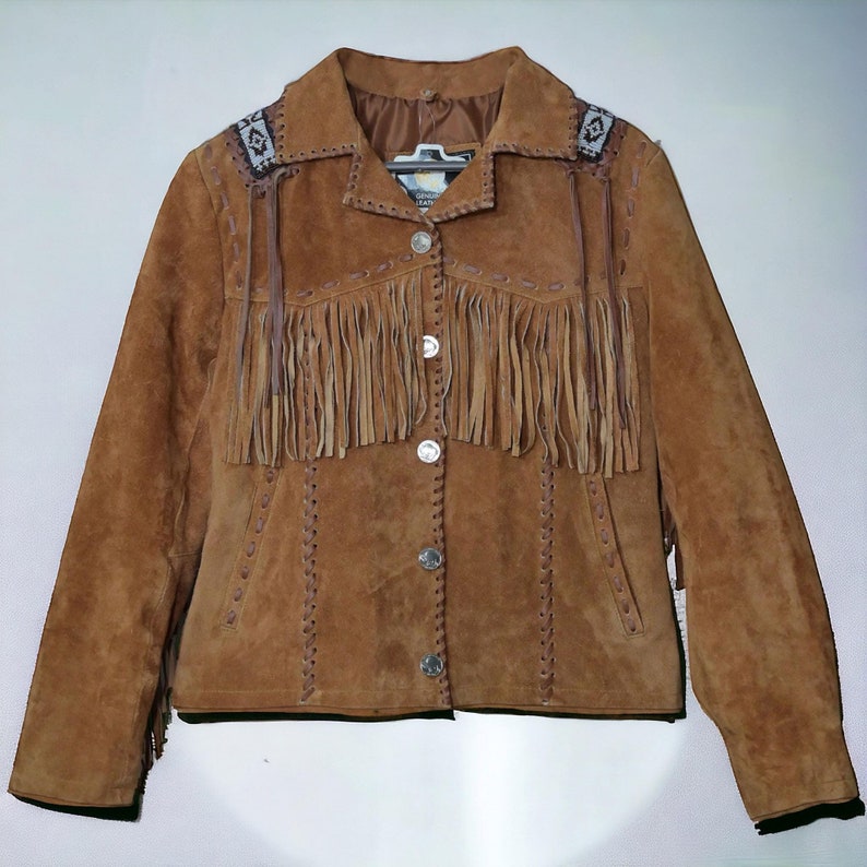 Women’s Western suede fringe jacket made from genuine suede leather with handmade beaded shoulder details, soft inside lining, and vintage cowgirl style. This tan boho Western jacket features long fringe accents, button front closure, and Southwestern-inspired craftsmanship. Perfect for rodeo fashion, country concerts, rustic Western wear, festival outfits, and bohemian street style. Stylish vintage leather jacket for women seeking authentic cowgirl fringe fashion and timeless Western charm.