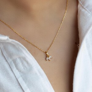 Op de afbeelding: Een delicate gouden ketting met een klein hangertje met drie heldere, marquisevormige stenen.