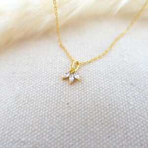 Op de afbeelding: Een delicate gouden ketting met een klein hangertje met drie heldere zirkonia-stenen.