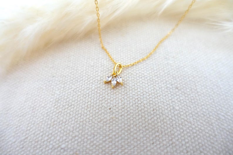 Op de afbeelding: Een delicate gouden ketting met een klein hangertje met drie heldere zirkonia-stenen.