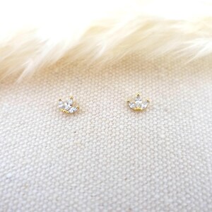 Op de afbeelding: Een paar gouden oorbel studs met kleine, heldere zirkonia stenen in de vorm van een kroon.