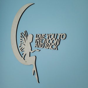 May include: Wooden cutout of a fairy sitting on a crescent moon with the text "Love you to the moon and back" on a light blue background.