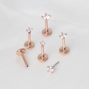 Op de afbeelding: Zes lichaamssieraden van ros&eacute;goud met heldere zirkonia-stenen. De stukken zijn in verschillende maten en stijlen verkrijgbaar, waaronder een oorbel, een labret en een helixring.