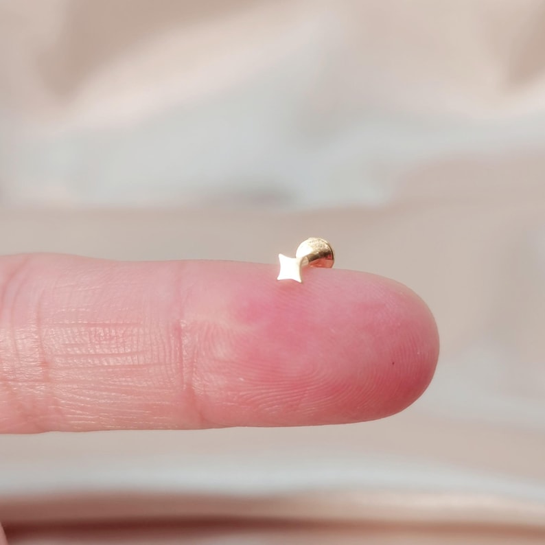 May include: A gold star-shaped stud earring with a small ball post.