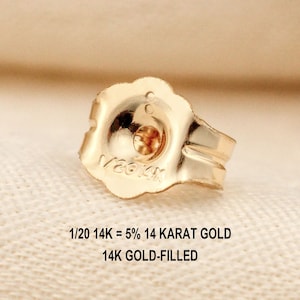 Puede incluir: Un cierre de pendiente de color dorado con borde festoneado, que presenta el texto grabado 1/20 14K. Debajo del cierre, el texto indica 1/20 14K = 5% 14 KARAT GOLD y 14K GOLD-FILLED, se&ntilde;alando la composici&oacute;n del componente met&aacute;lico.