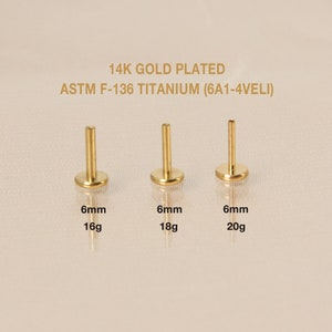 May include: Three gold-plated titanium body jewelry pieces, each with a 6mm diameter and different gauge sizes: 16g, 18g, and 20g. The jewelry is labeled with the gauge size and the text "14K GOLD PLATED ASTM F-136 TITANIUM (6A1-4VELI)".