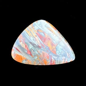May include: A polished, triangular gemstone with a blend of colors. The stone features a mix of blue, orange, red, and yellow hues, creating a marbled effect. The gemstone is set against a black background.