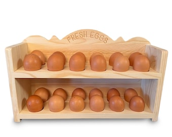 May include: A wooden egg holder with two shelves, filled with brown eggs. The top of the holder has the words "FRESH EGGS" carved into the wood. The eggs are evenly spaced, creating a neat display.