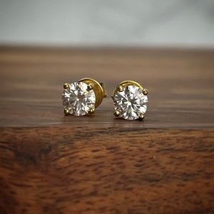 May include: A pair of gold stud earrings with round, clear cubic zirconia stones.