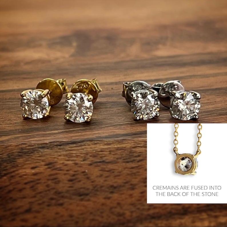 May include: Two pairs of diamond stud earrings, one pair in gold and one pair in silver. The earrings are shown on a wooden surface. A close-up of a pendant necklace with a round diamond stone is also shown. The text "CREMAINS ARE FUSED INTO THE BACK OF THE STONE" is below the pendant.
